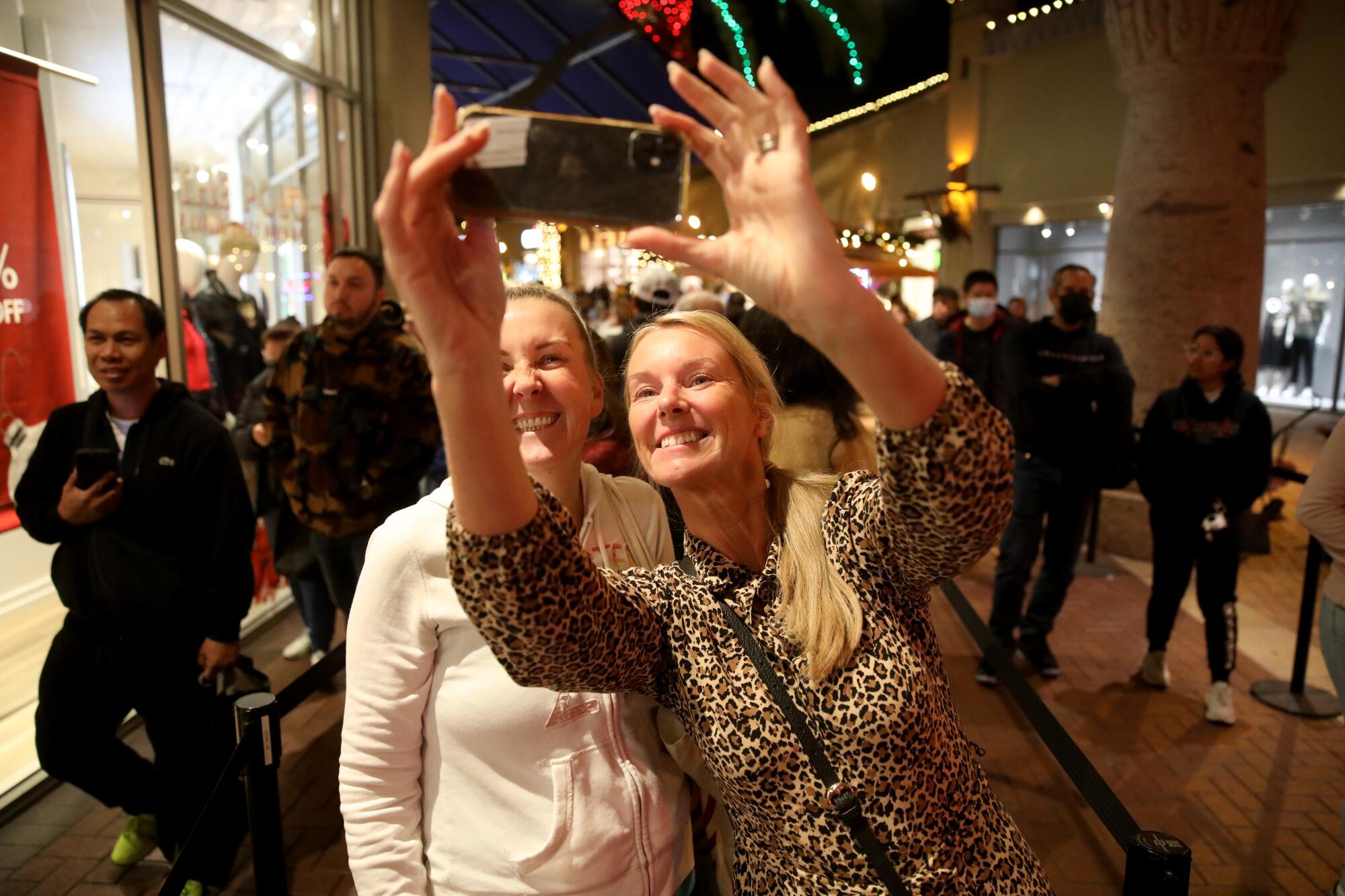 Two women wait to get into the Tommy Hilfiger store on Black Friday at the Citadel Outlets in Commerce