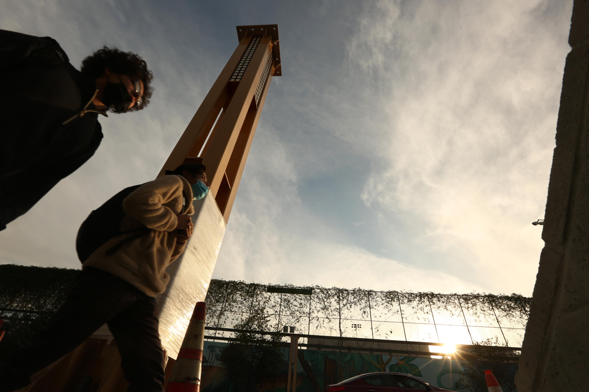 People walk past one of the columns that will make up the gateway arch in Historic Filipinotown.