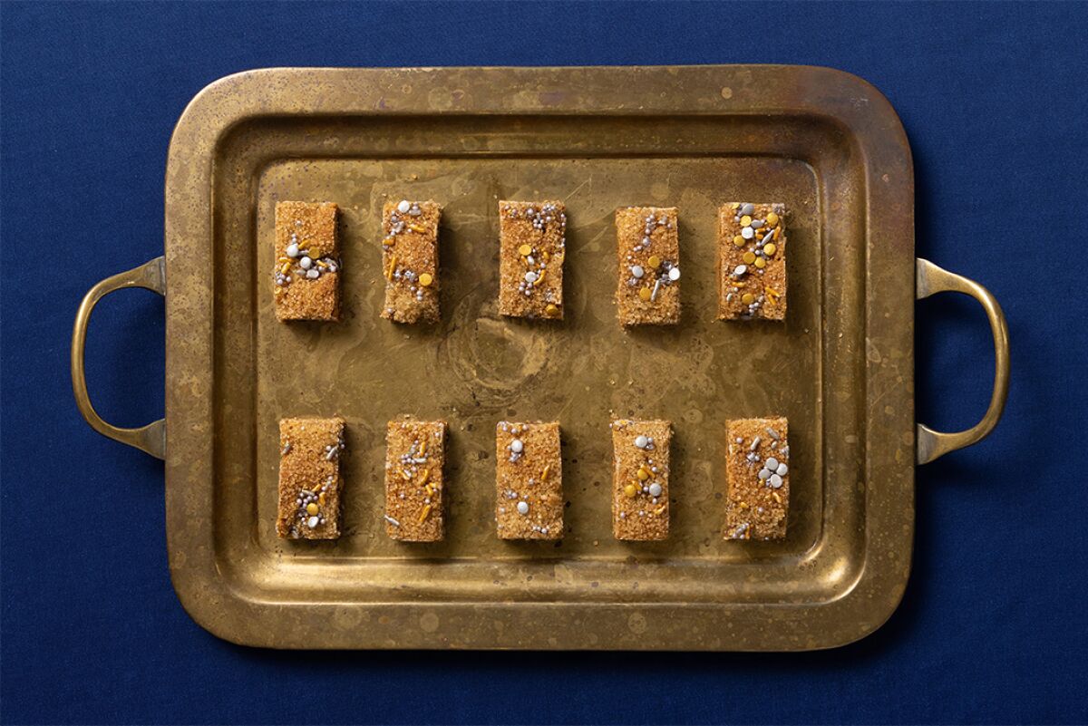 Golden rectangular cookies spaced out on a metal baking sheet.