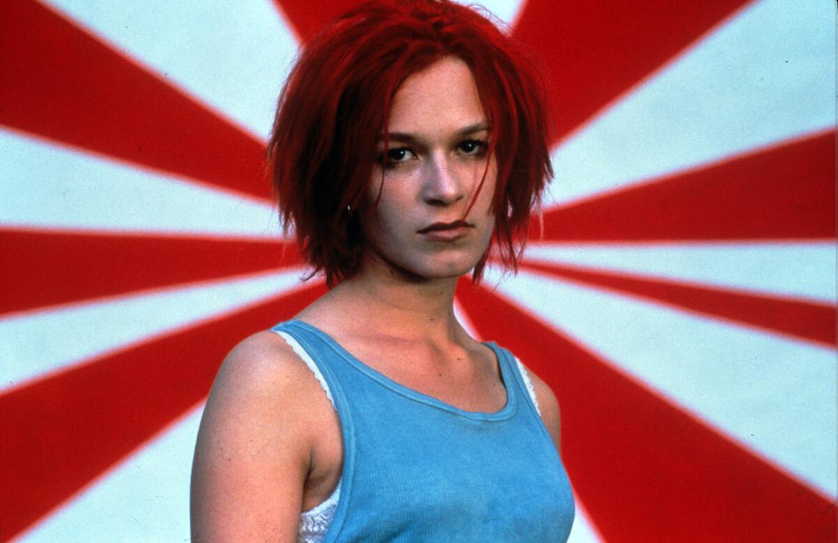 A woman with red hair stares down the camera.