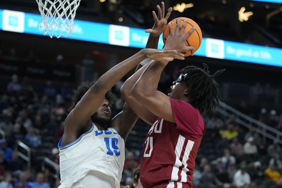 UCLA's Myles Johnson (15) guards Washington State's Dishon Jackson (21) during the first half of an NCAA college basketball game in the quarterfinal round of the Pac-12 tournament Thursday, March 10, 2022, in Las Vegas. (AP Photo/John Locher)