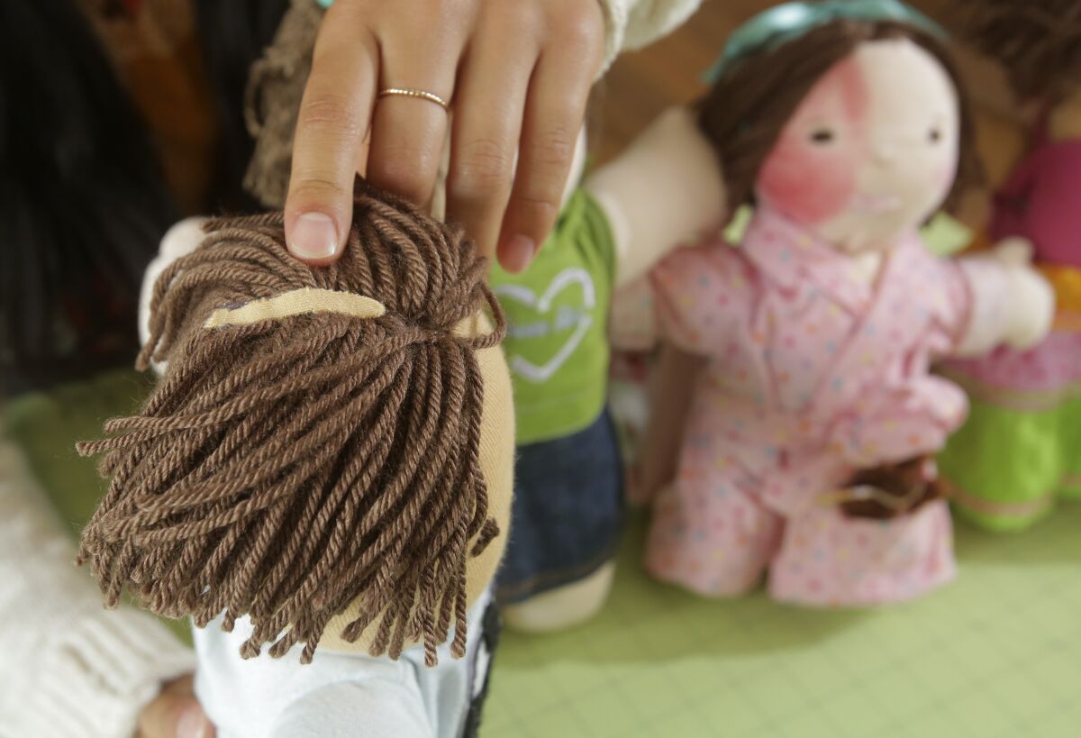 Ariella Pacheco, 17, shows a boy doll she made with a scar on his head.   