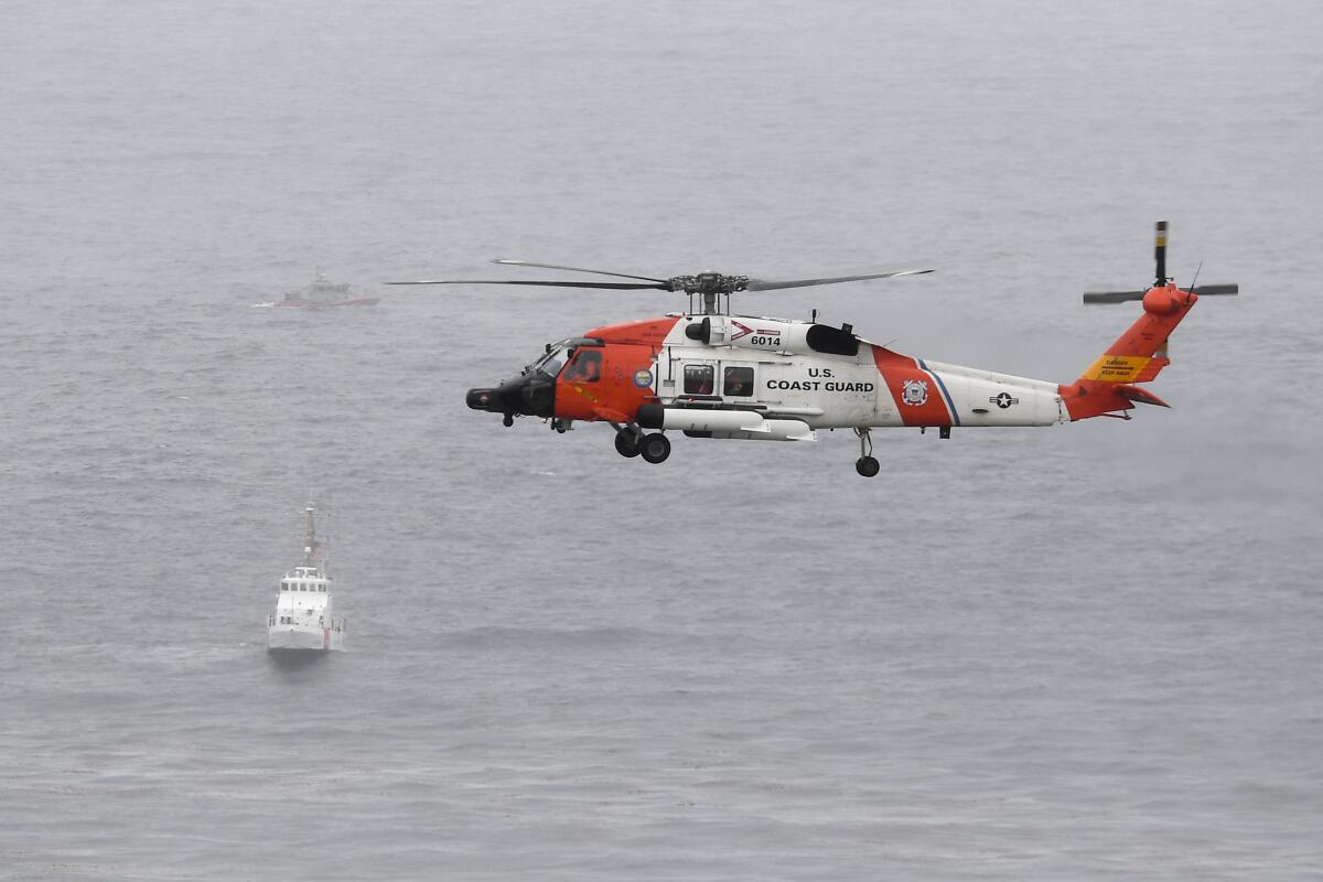 A helicopter is seen flying over a boat.