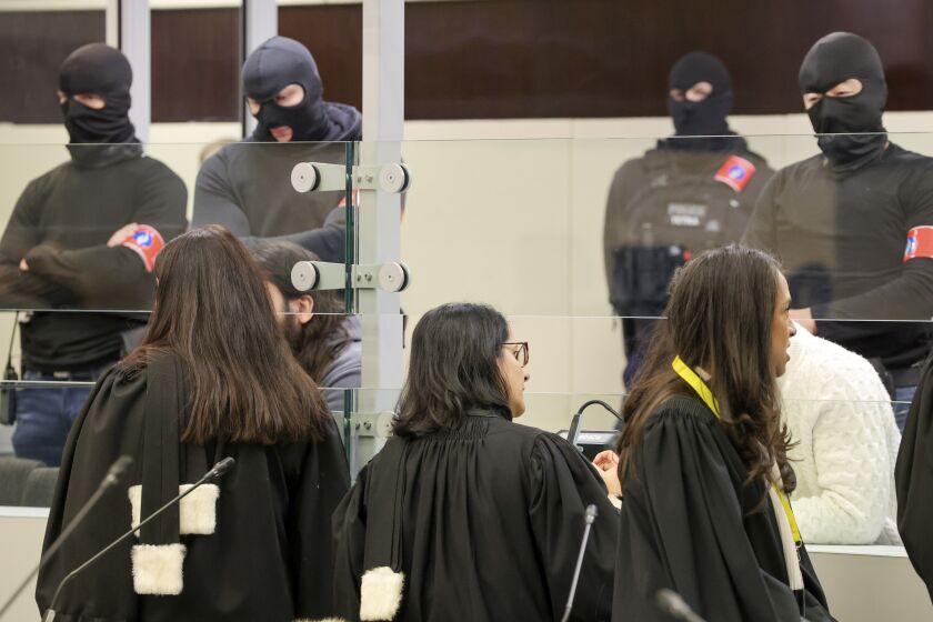 Lawyers speak with defendants through the glass of a specially designed glass box during the start of the trial for the Brussels attacks, that took place on March 22, 2016, at the Justitia building in Brussels, Monday, Dec. 5, 2022. More than six years later, ten defendants face charges including murder, attempted murder and membership, or participation in the acts of a terrorist group, over the morning rush hour attacks at Belgium's main airport and on the central commuter line on March, 22, 2016. (AP Photo/Olivier Matthys, Pool)
