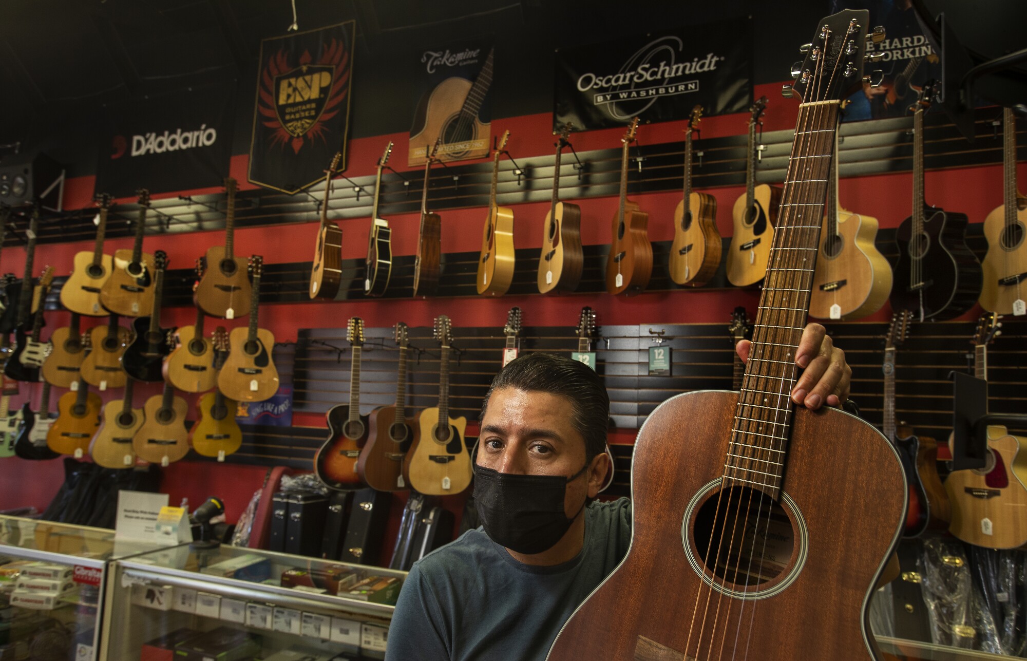 Jose Antonio Olvera, 49, owner of Olvera Music, holds a guitar