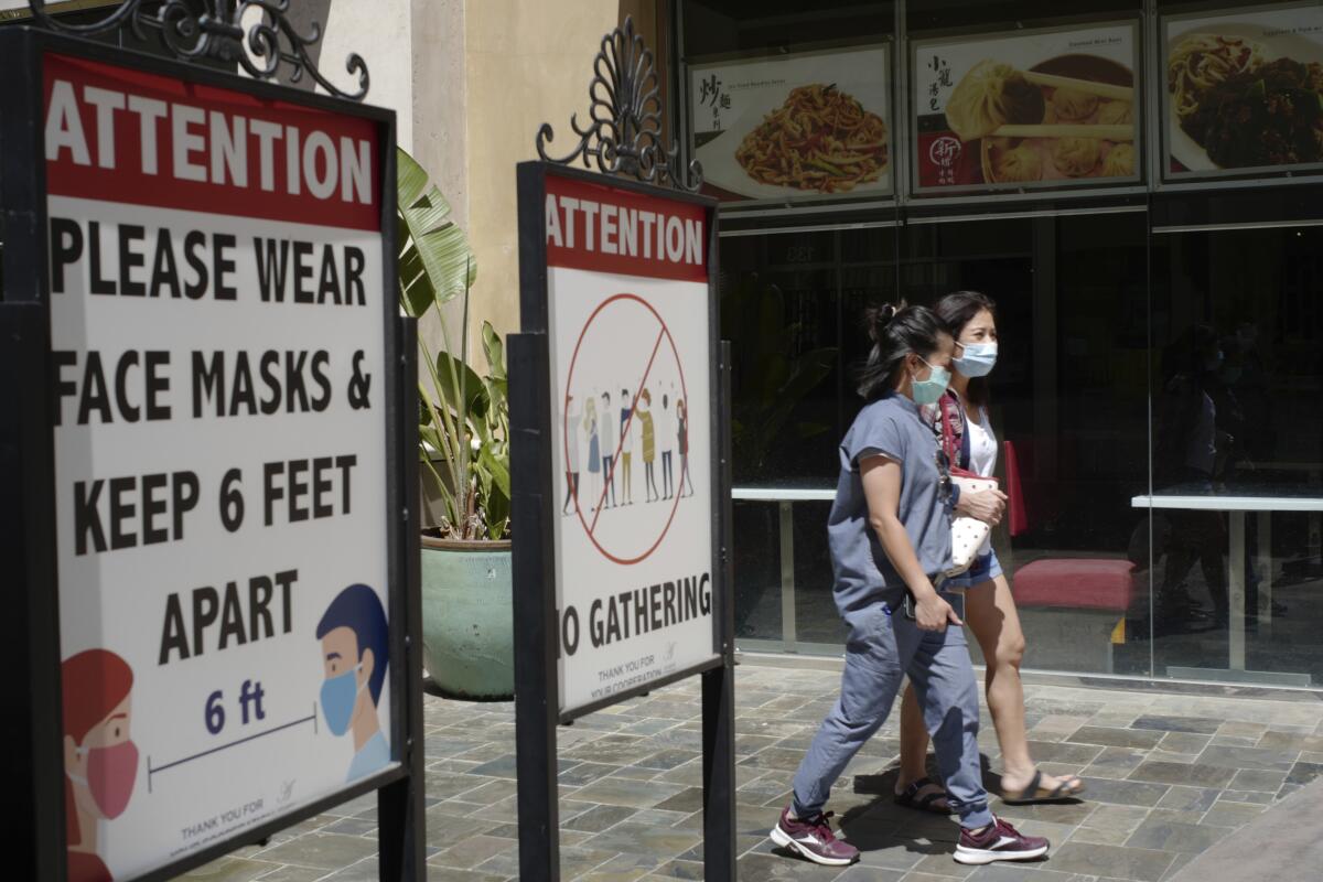 Personas con cubrebocas caminan en el exterior de un centro comercial