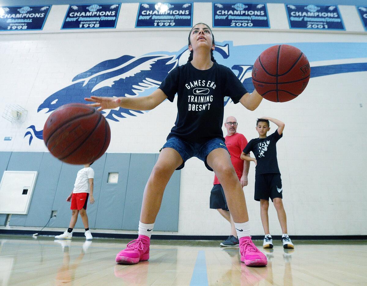 Lucia Arzoumanian, 13, of La Crescenta, dribbles with two basketballs at the same time as she practices dribbling drills at the Coach Z Basketball Camp at Crescenta Valley High School on Monday, July 22, 2019. Coach Shawn Zargarian coordinated basketball drills with helping coaches to keep about 50 youth basketball enthusiasts busy.