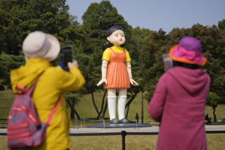 Visitors take photos near a model of the doll named 'Younghee' featured in Netflix's series "Squid Game"