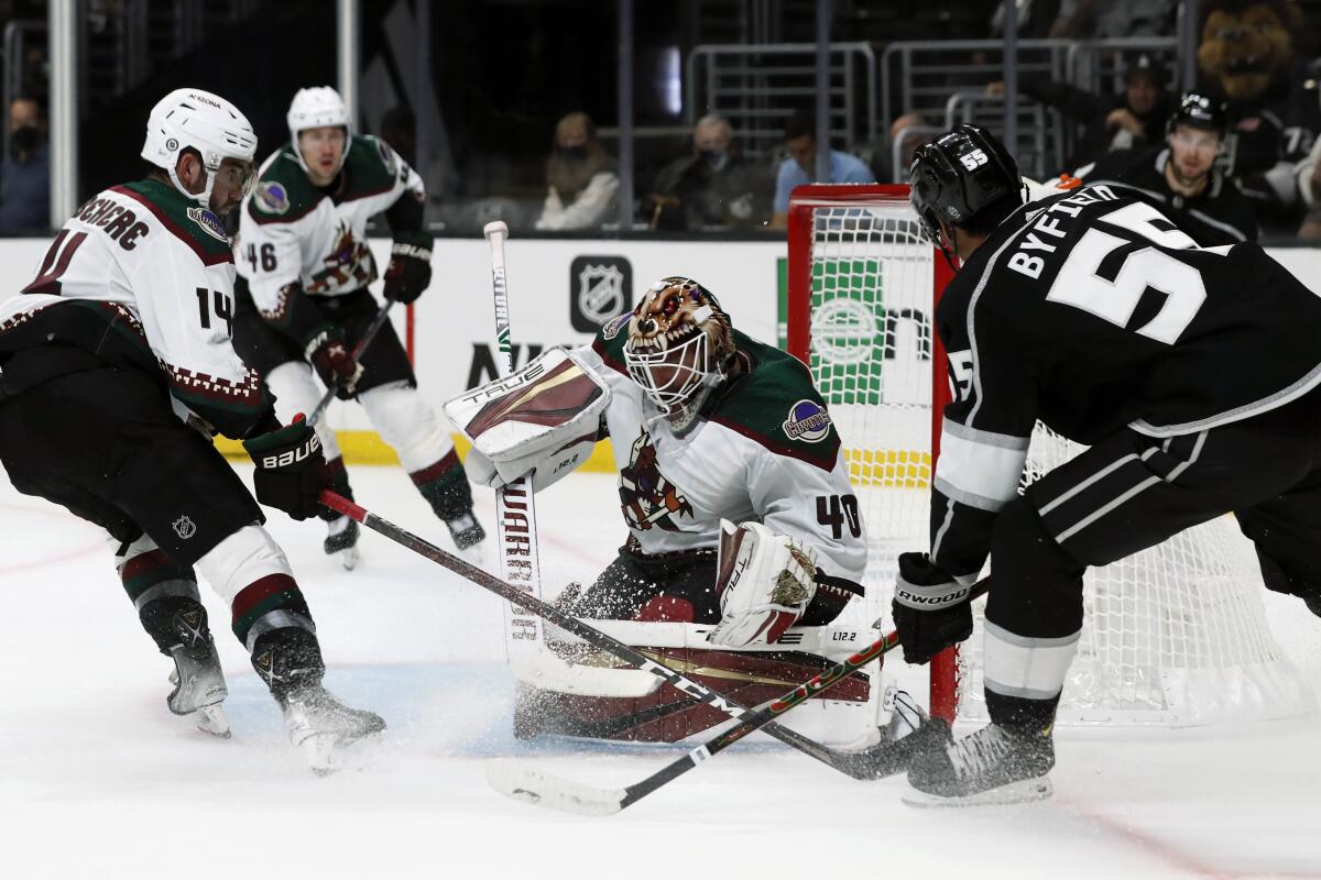 Arizona Coyotes goaltender Carter Hutton (40) stops a shot by Los Angeles Kings center Quinton Byfield, right, with defenseman Shayne Gostisbehere (14) defending during the second period of a preseason NHL hockey game in Los Angeles, Tuesday, Oct. 5, 2021. (AP Photo/Alex Gallardo)