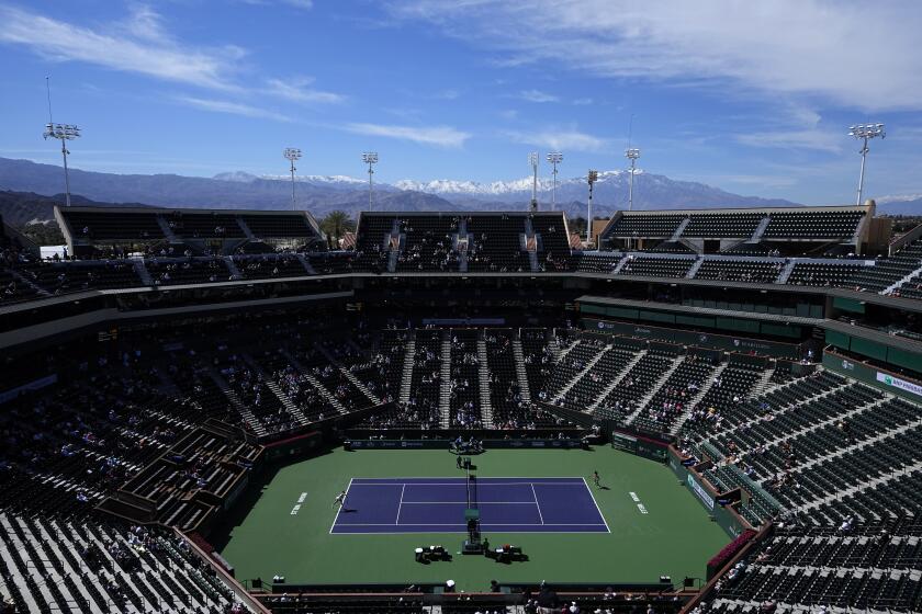 Snow covers area mountaintops as Danka Kovinic, of Montenegro, left, serves to Emma Raducanu.