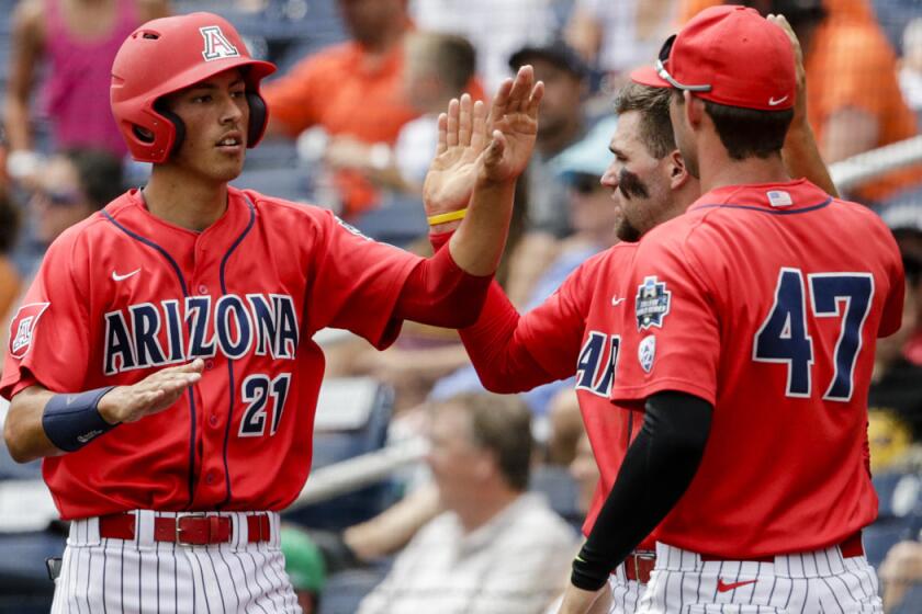 Arizona's Ryan Aguilar, left, celebrates with teammates after scoring on a sacrifice fly by Jared Oliva during the first inning of a College World Series baseball game against Oklahoma State on Saturday.