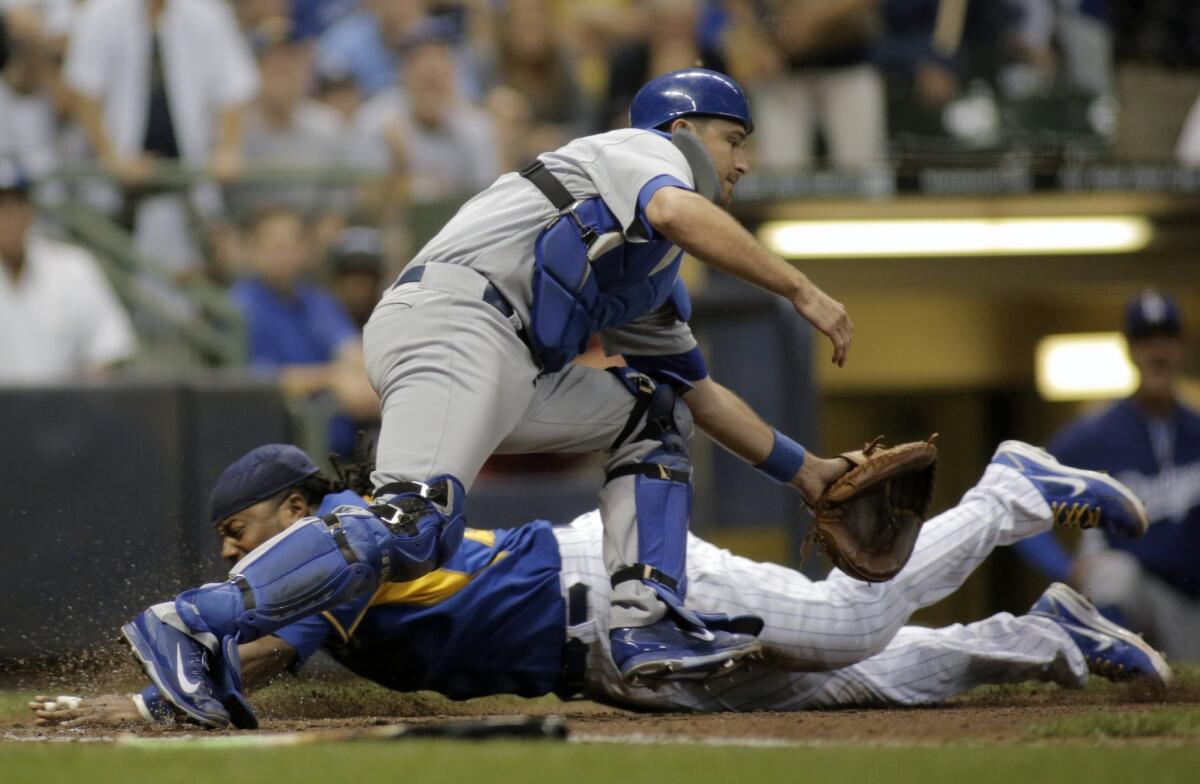 Milwaukee's Rickie Weeks, back, scores in front of catcher Drew Butera during the seventh inning of the Dodgers' 9-3 loss to the Brewers on Friday at Miller Park.