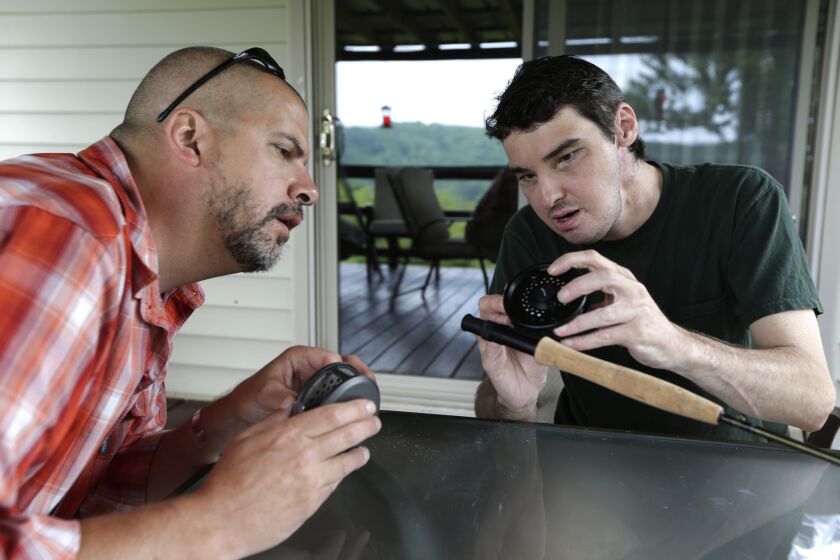 Richard Norris, right, shows friend Andrew Kahle how to load line into a fly fishing rod at Norris' home in Hillsville, Va. Norris, whose face was disfigured by a gunshot, received a face transplant in 2012.