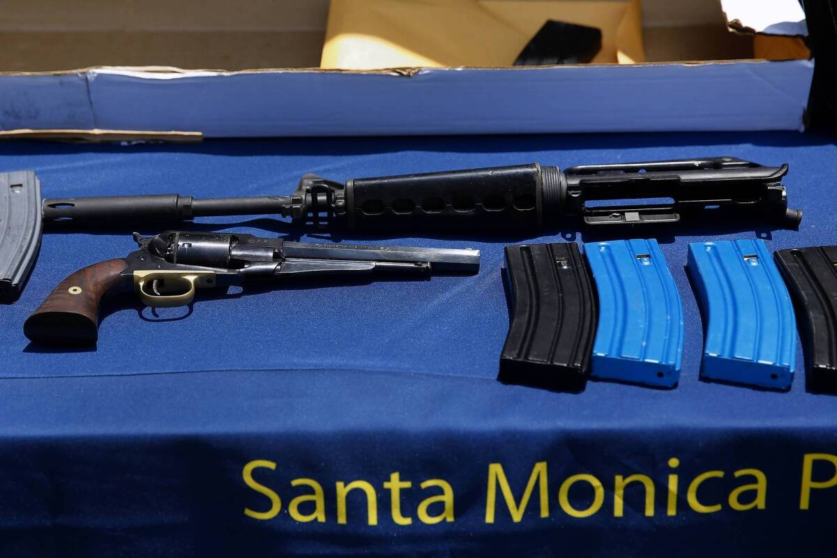 A table of evidence collected in the Santa Monica shooting investigation includes a .44-caliber handgun and the upper receiver of an AR-15-style rifle.