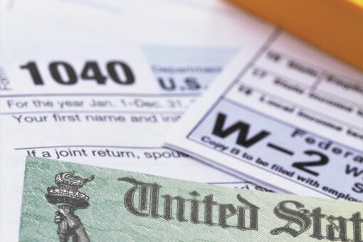 1040 income tax form and w-2 wage statement with a federal Treasury refund check. Closeup with selective focusing.