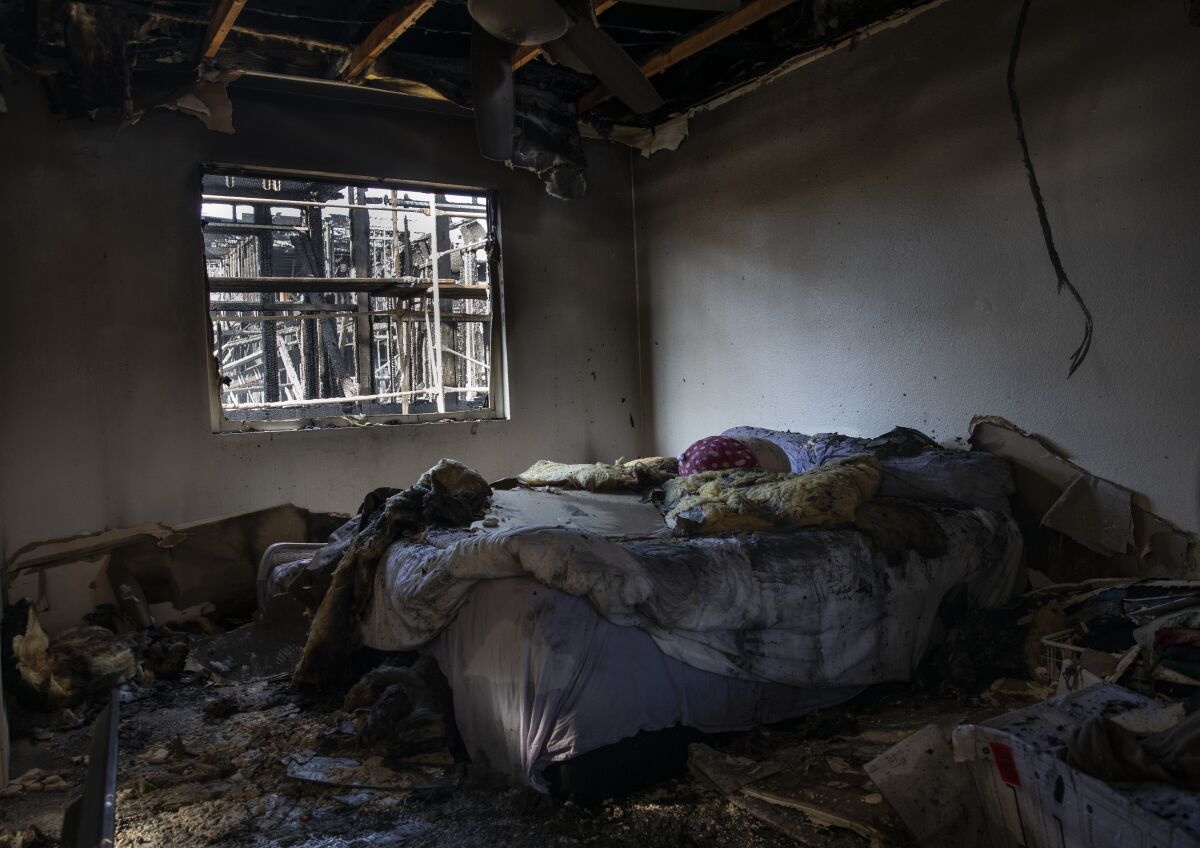 Charred debris from a collapsed ceiling litters a burned bedroom after a fire.