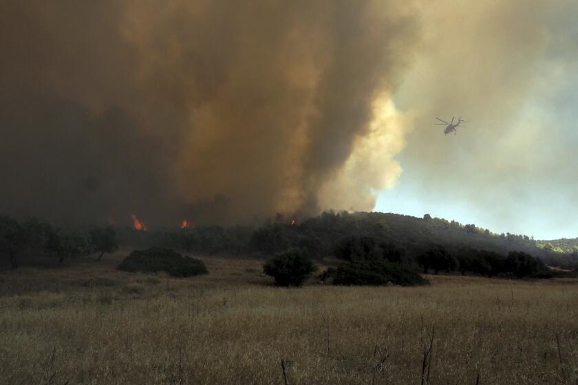 A helicopter flies over a wildfire near Vatontas village on the Aegean Sea island of Evia, Greece, Monday, Aug. 21, 2023. Major wildfires were burning in Greece and on one of Spain's Canary Islands off the African coast Monday, with hot, dry and windy conditions hampering the efforts of hundreds of firefighters battling the blazes, two of which have been burning for several days. (AP Photo/Thodoris Nikolaou)