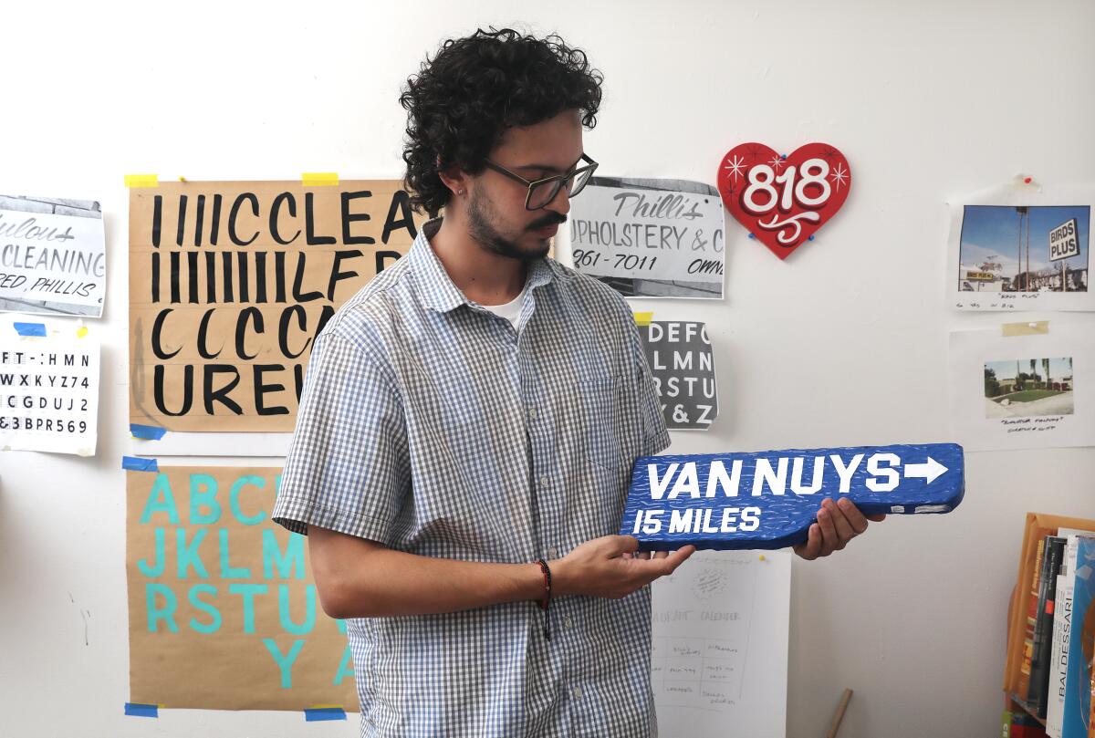 Vincent Enrique Hernandez holds up a sign reading "VAN NUYS, 15 miles."