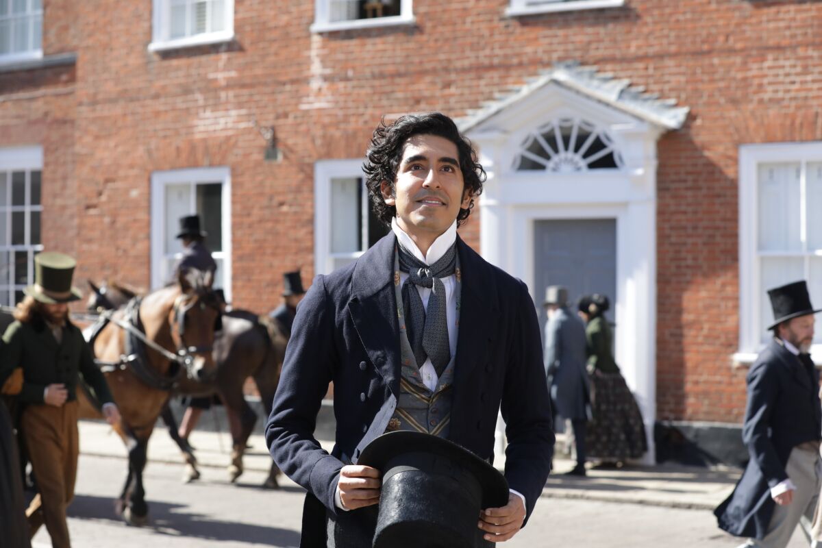 Dev Patel wearing a black suit and holding a top hat in "The Personal History of David Copperfield."