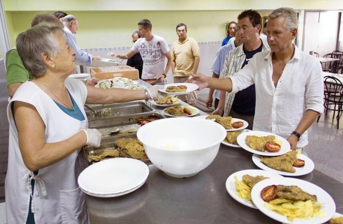 Volunteers serve meals at a charity dining hall in Valencia, Spain. Close family ties are another factor that has enabled the nation to withstand a nearly 25% unemployment rate.