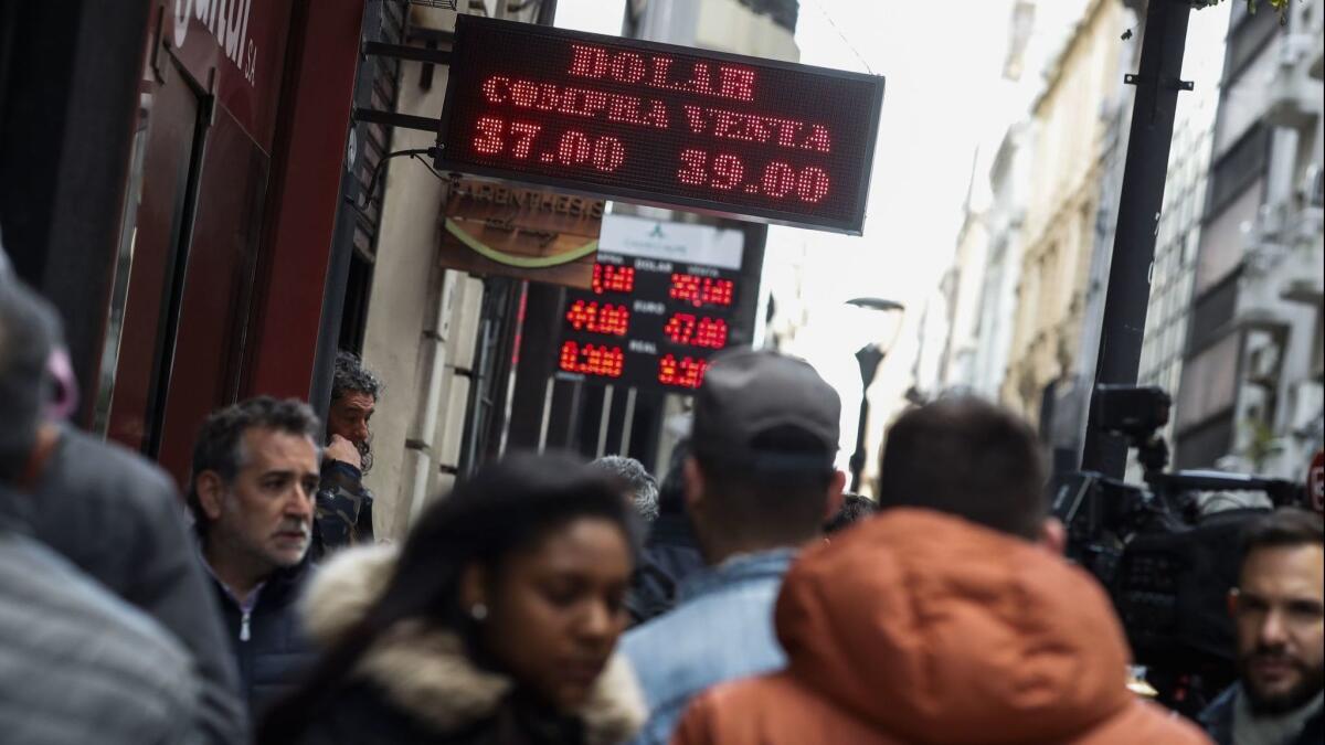 Pedestrians walk past currency exchange houses in the center of Buenos Aires on Friday.