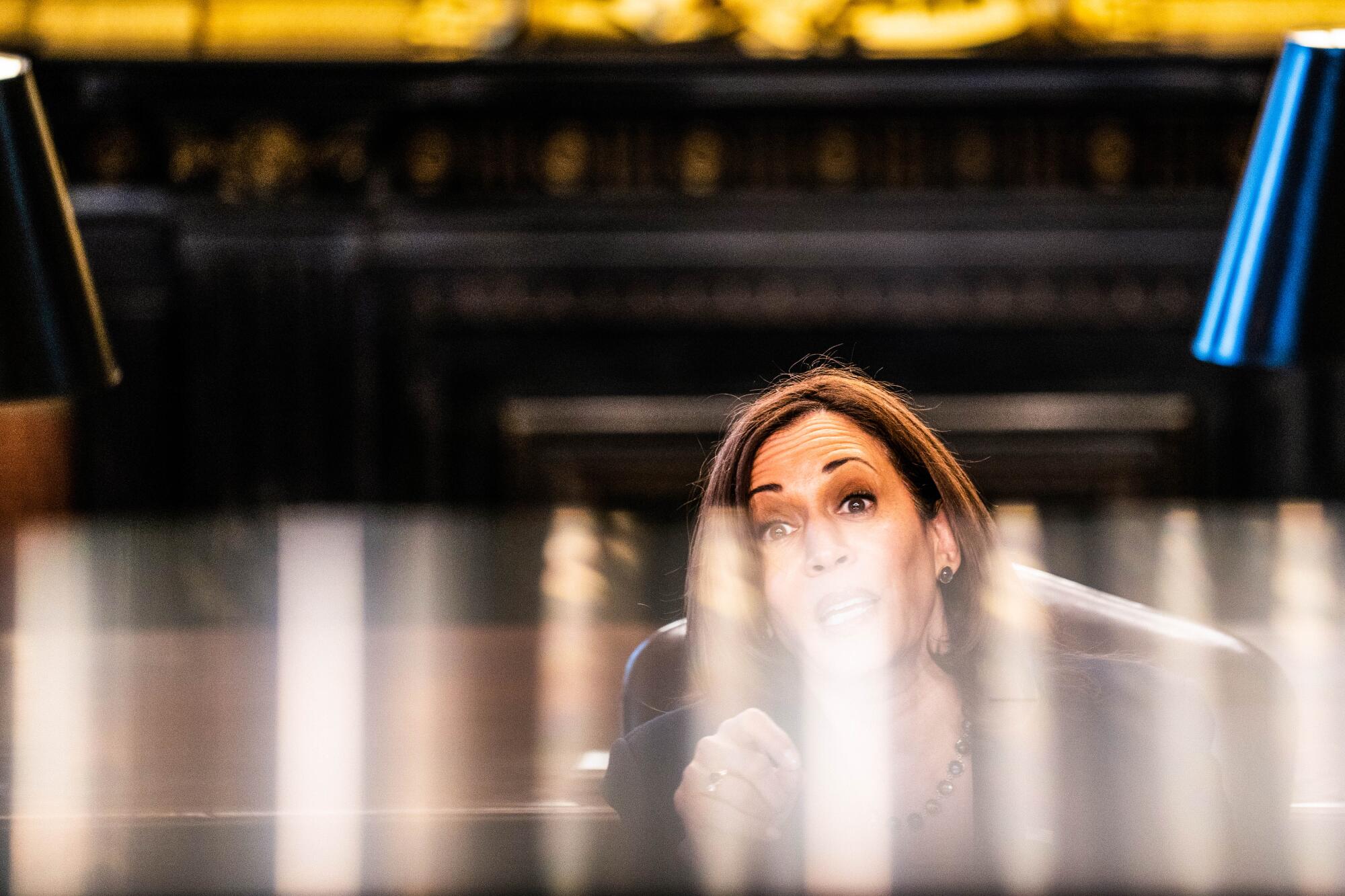 Kamala Harris is seen through a plexiglass partition.