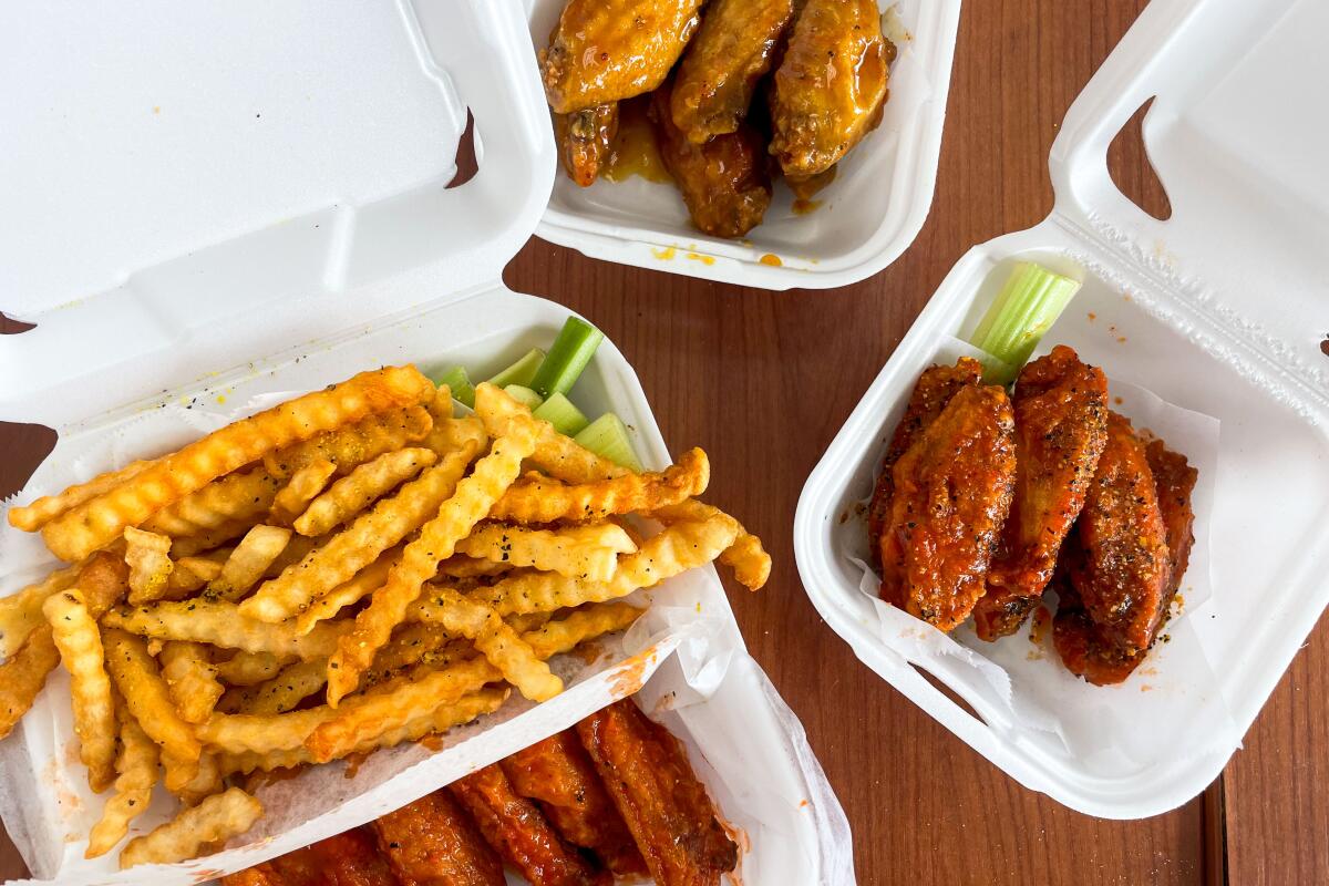 Styrofoam containers of fries and assorted chicken wings