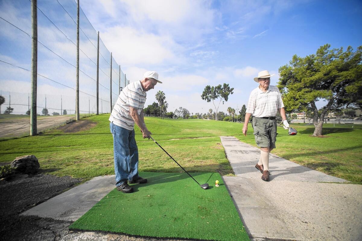Louie Donaher sets up for a tee shot as Robert McKenzie walks past during a round at Newport Beach Golf Course.