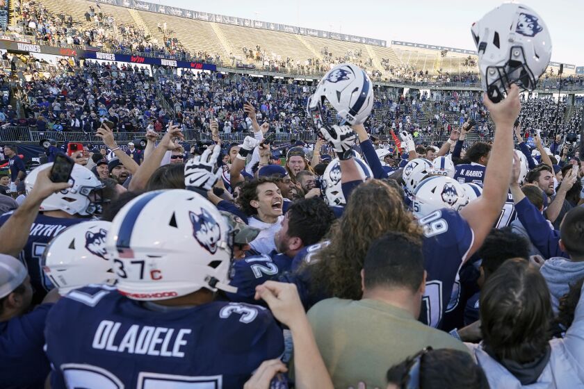 Fans stormed the field and celebrate with players after Connecticut defeated Liberty in an NCAA college football game in East Hartford, Conn., Saturday, Nov. 12, 2022. (AP Photo/Bryan Woolston)