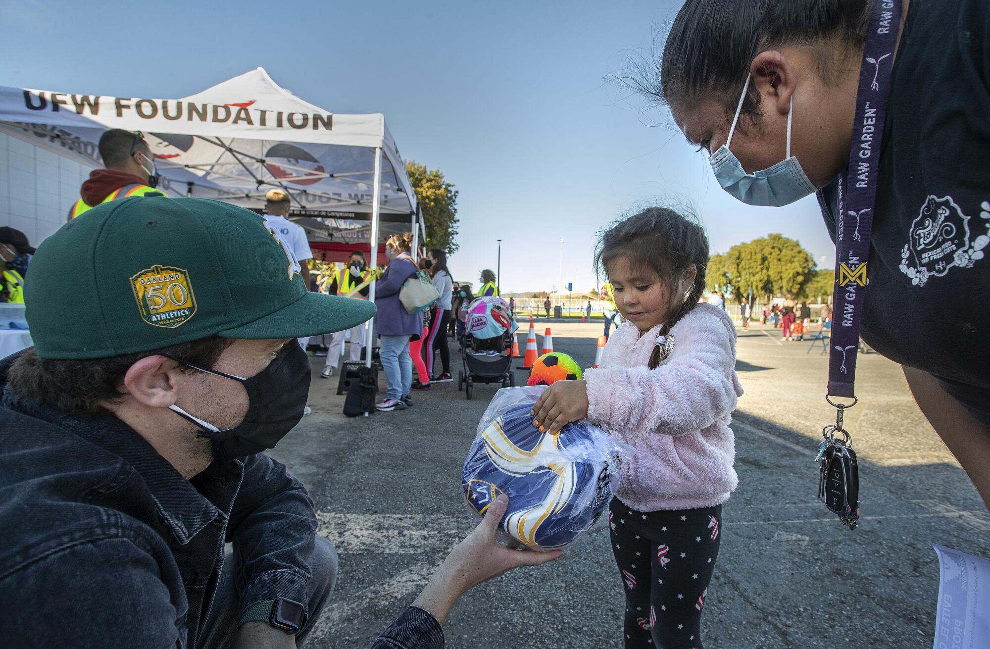 Adam Serrano, left, Social Media Lead for the Los Angeles Galaxy, gives a soccer ball to Thalia Lopez.