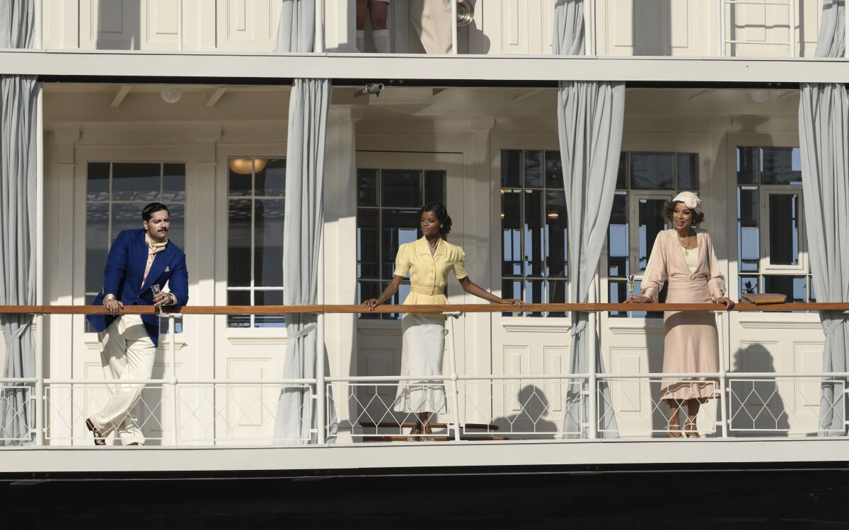 Ali Fazal, Letitia Wright and Sophie Okonedo look out from a deck on a cruise ship in the movie "Death on the Nile."