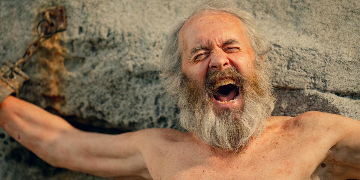 A man chained to a mountain, grimacing in pain with his mouth open.