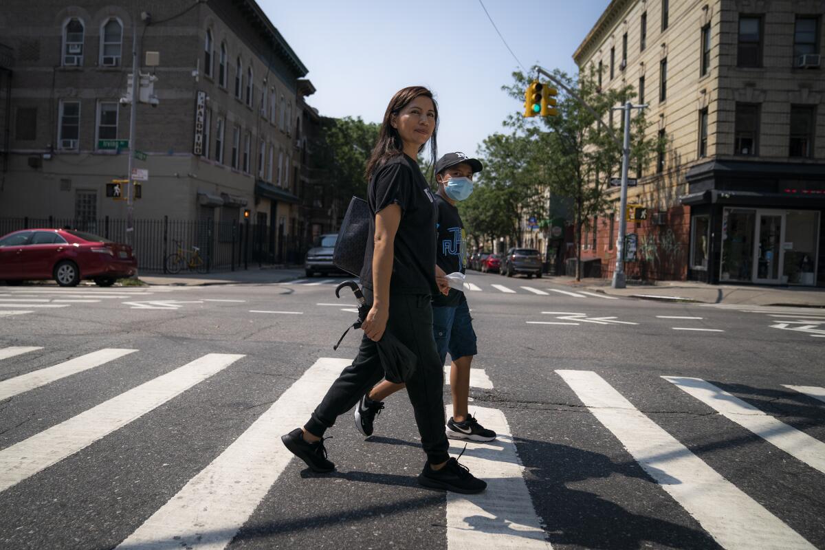 Monica Muquinche and her son Sebastian walk to a park in their neighborhood in the Brooklyn borough of New York, Thursday, Aug. 26, 2021. Muquinche, whose husband disappeared in 2020 while trying to reach the U.S., is part of an extraordinary wave of Ecuadorians coming in the United States. (AP Photo/John Minchillo)