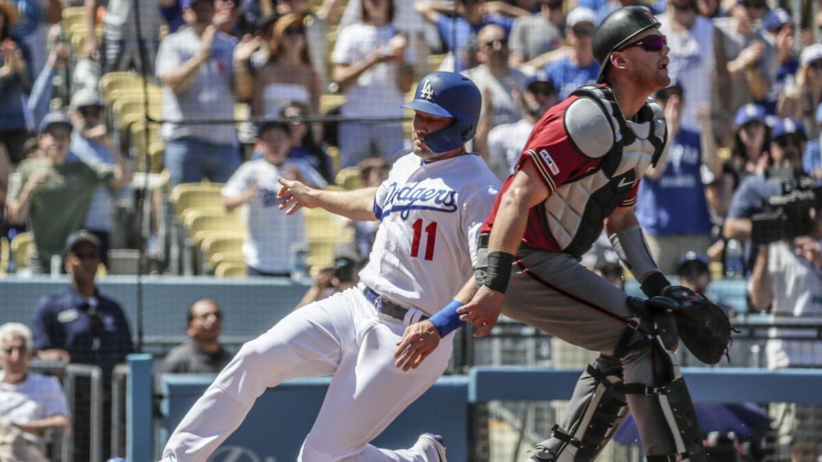 A.J. Pollock slides into home on an Alex Verdugo double as Diamondbacks catcher Carson Kelly awaits the throw in the first inning at Dodger Stadium on Sunday.