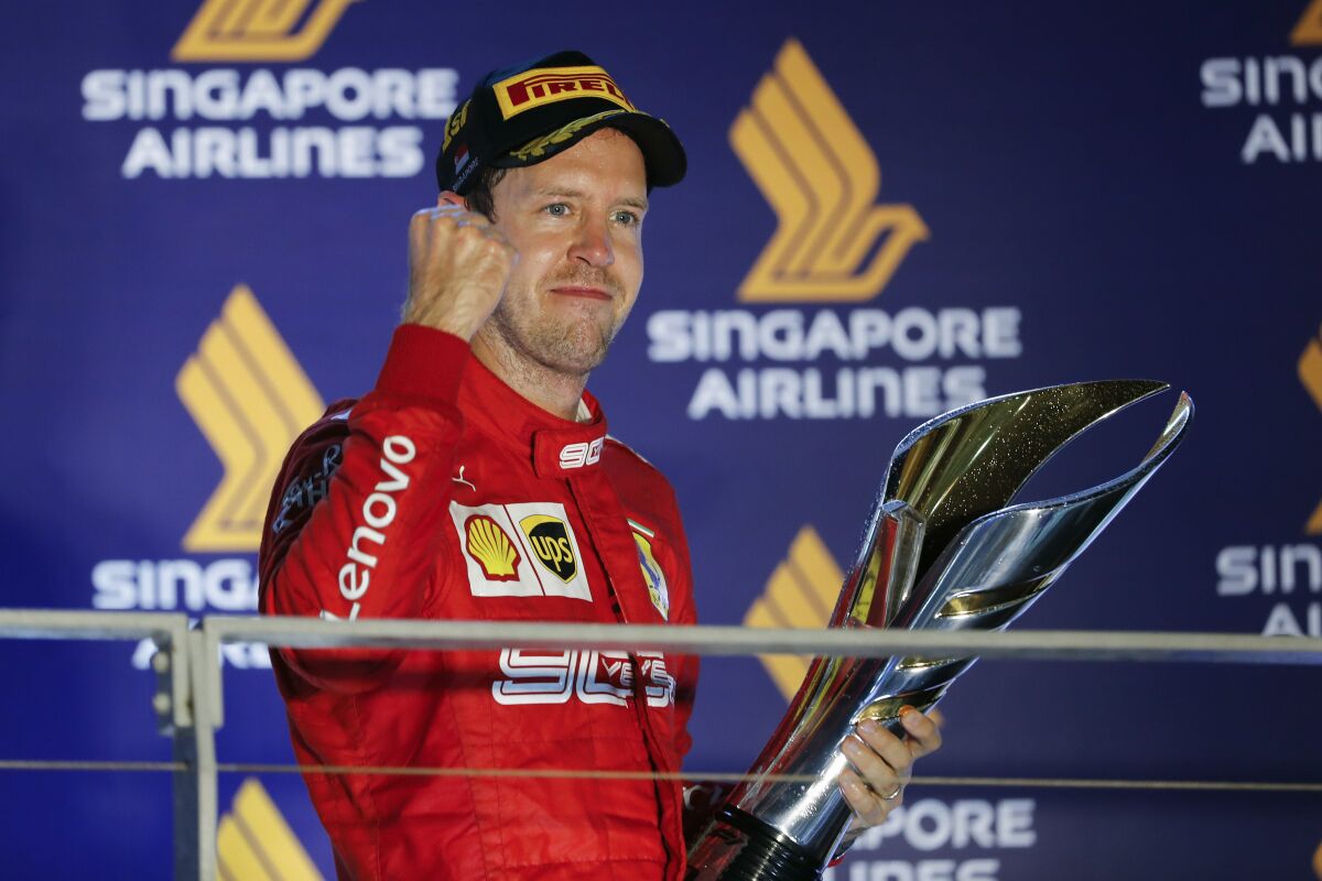 Ferrari driver Sebastian Vettel celebrates with the trophy after winning the Singapore Grand Prix on Sunday.