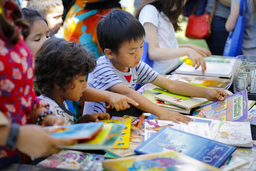 Five-year-old Jefferson Jensen, center, along with other children, look through books at the Kids READ! booth, during the San Diego Union-Tribune Festival of Books, at Liberty Station, August 24, 2019, in San Diego, California.