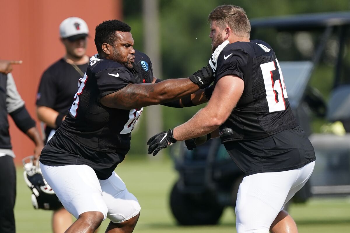Atlanta Falcons offensive guards Josh Andrews (68), left, and Ryan Neuzil (64) run a drill during the team's NFL training camp football practice Monday, Aug. 9, 2021, in Flowery Branch, Ga. (AP Photo/John Bazemore)