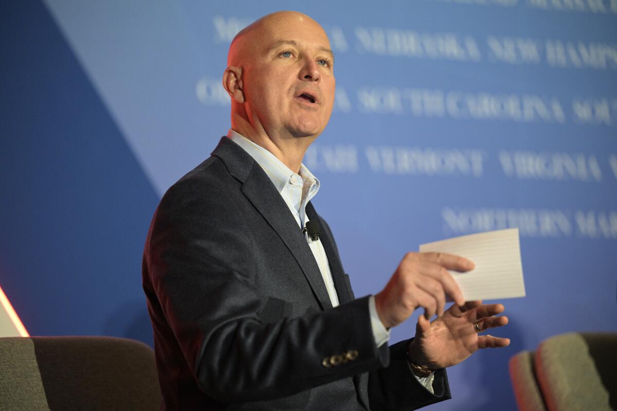 A man holding a notecard and speaking from a stage