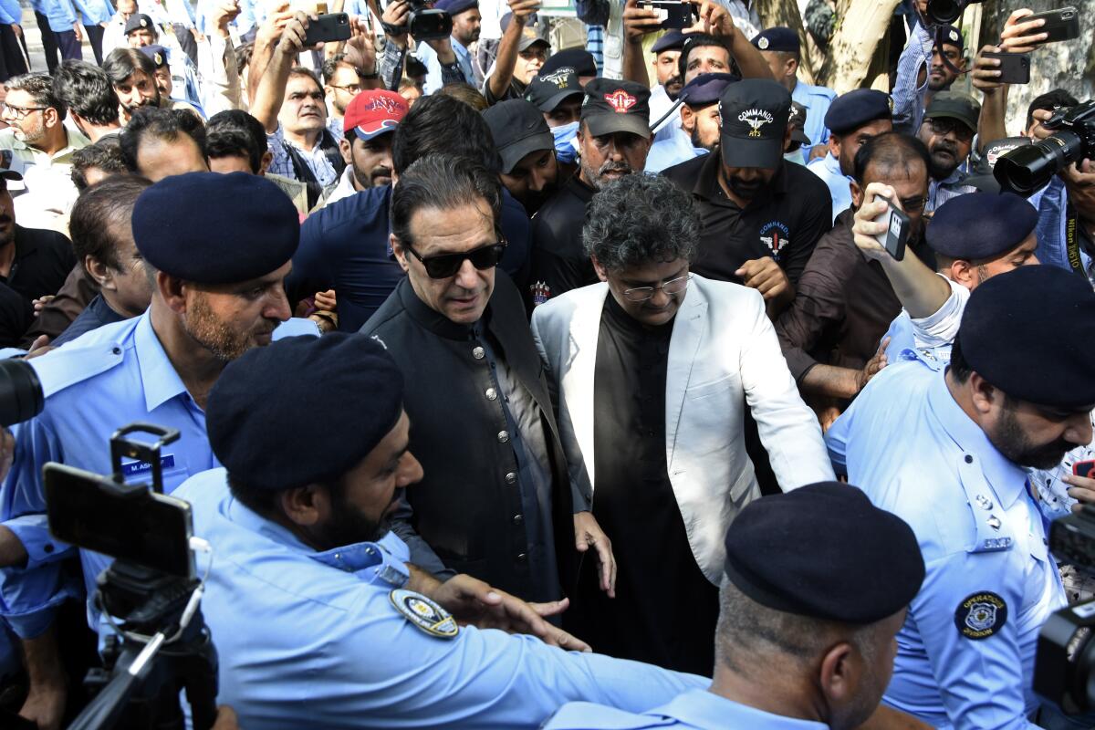 Former Pakistani Prime Minister Imran Khan, center, arrives to the Islamabad High Court surrounded by journalists and security in Islamabad, Pakistan, Thursday, Sept. 8, 2022. Khan appeared in court on Thursday and refused to formally apologize in a case in which he faces contempt charges over his verbal threat to a female judge during a political rally last month. (AP Photo/W.K. Yousafzai)