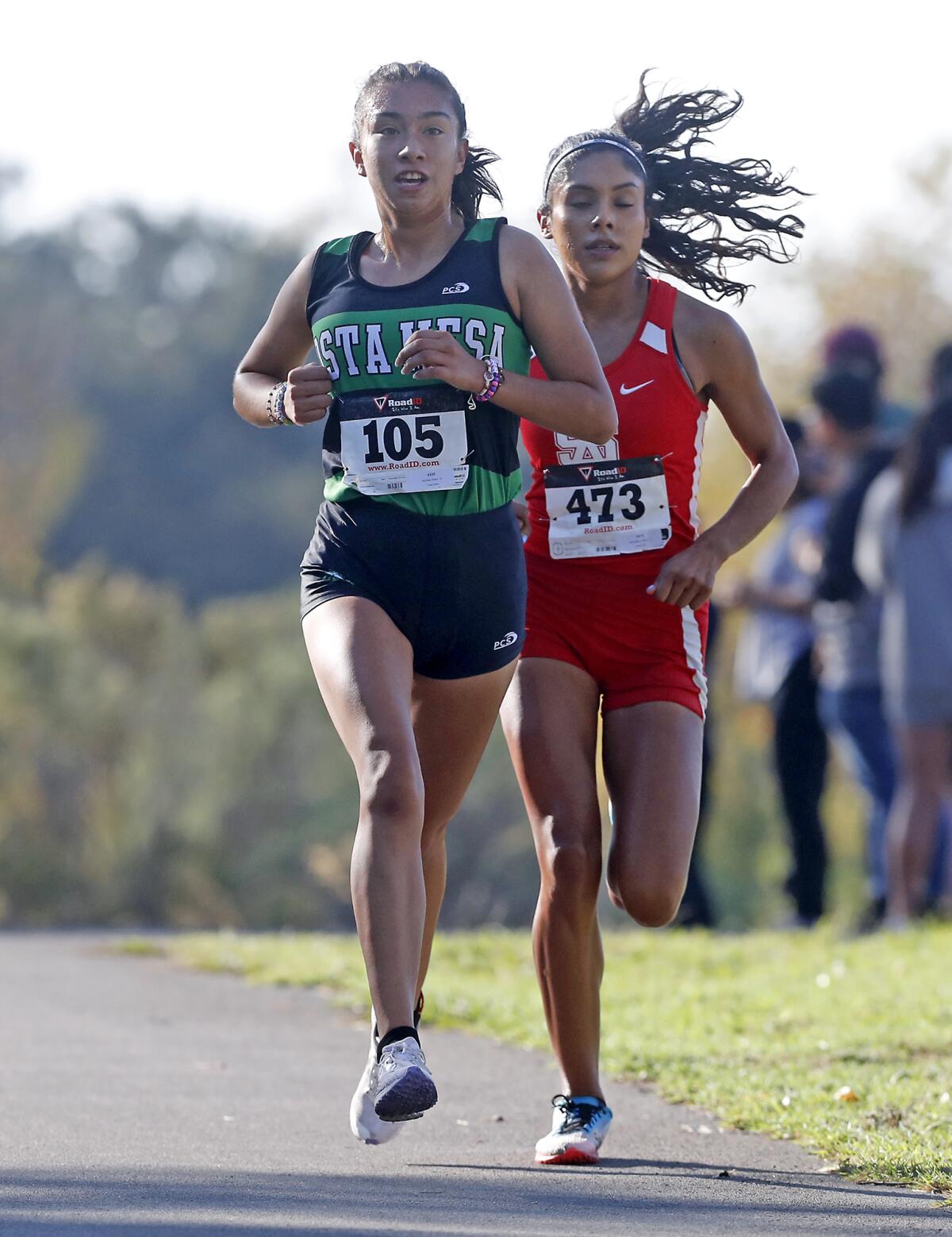 Costa Mesa's Diane Molina, left, and Santa Ana's Maria Hernandez compete during the first lap of the Orange Coast League girls' finals at Irvine Regional Park in Orange on Tuesday.