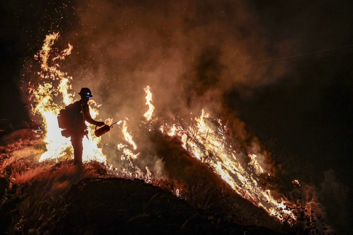 A firefighter battles the Bobcat fire at night.