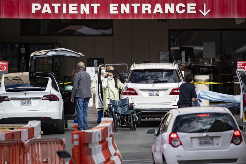 LOMA LINDA, CA - MARCH 17, 2020: Medical personnel tend to patients before screening them outside the Emergency Room at Loma Linda University Health during the coronavirus pandemic on March 17, 2020 in Loma Linda, California. (Gina Ferazzi/Los AngelesTimes)