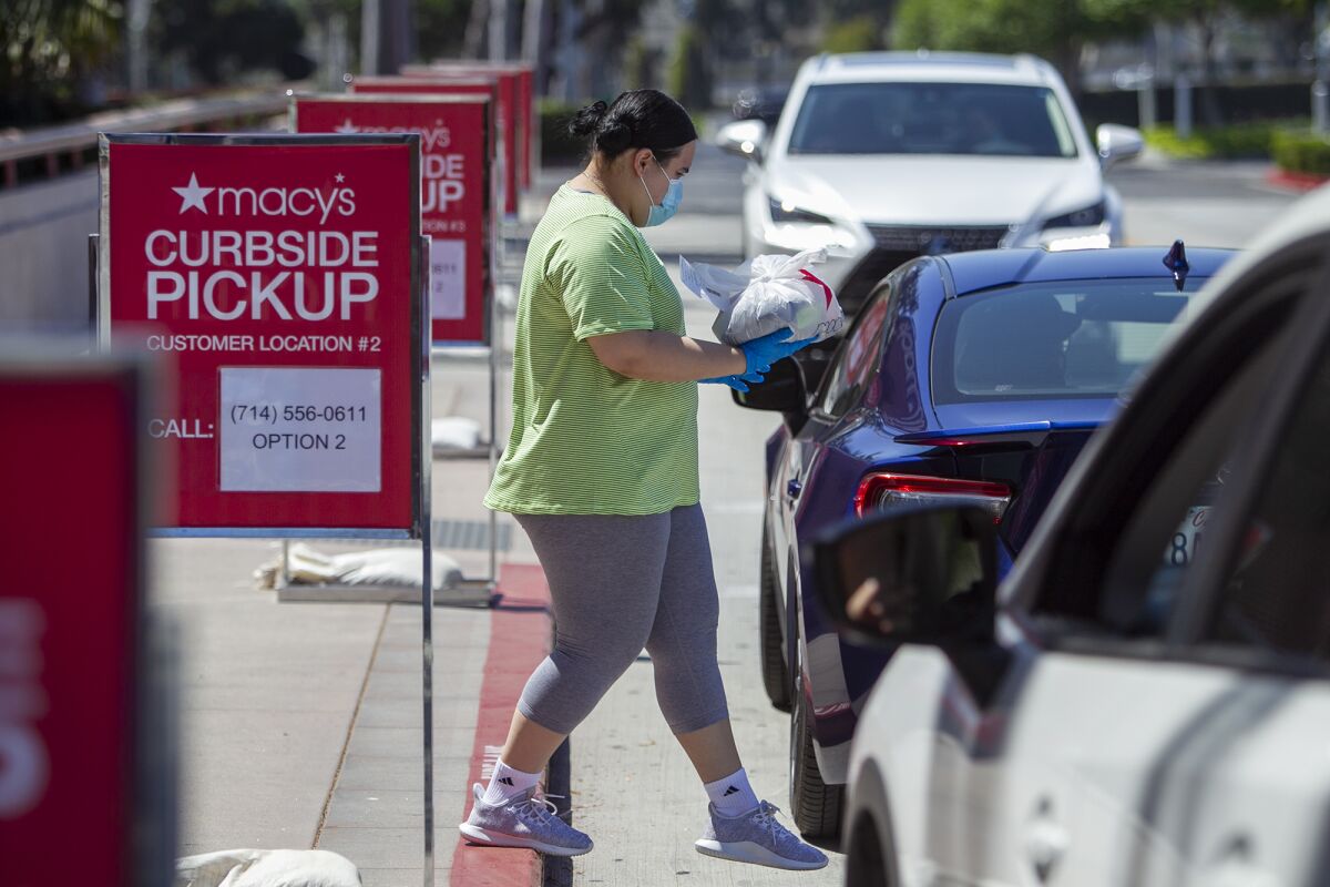 Miriam Lopez delivers a shirt to Von Eclevia on the curb at Macy's South Coast Plaza on May 8.