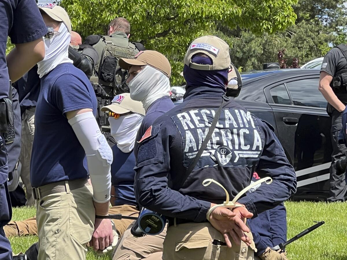 Men in balaclavas kneeling with their wrists tied