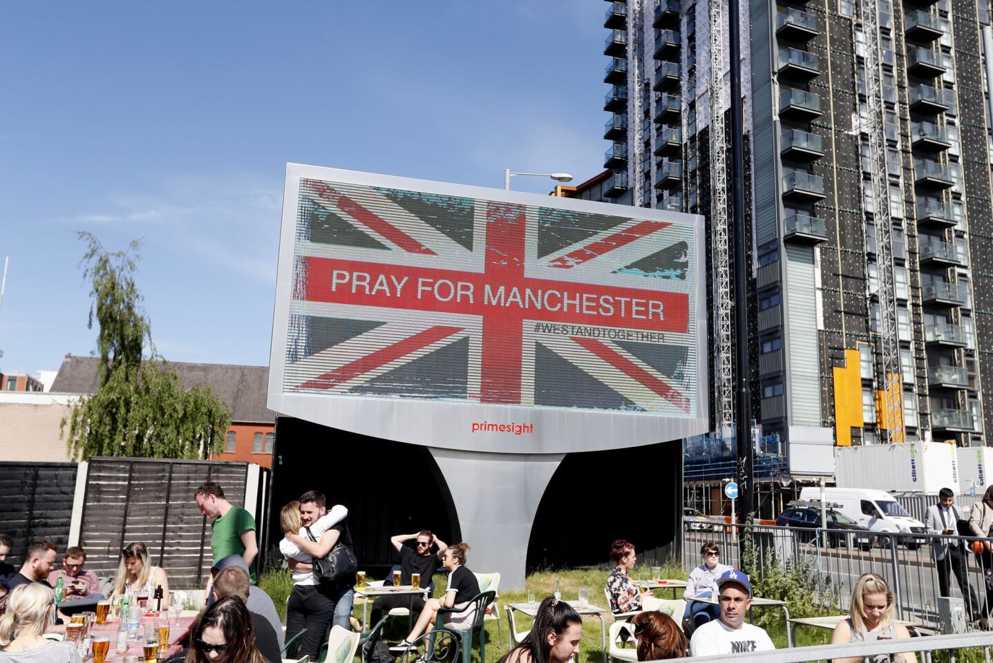 People sit under a billboard in Manchester city center on Tuesday.