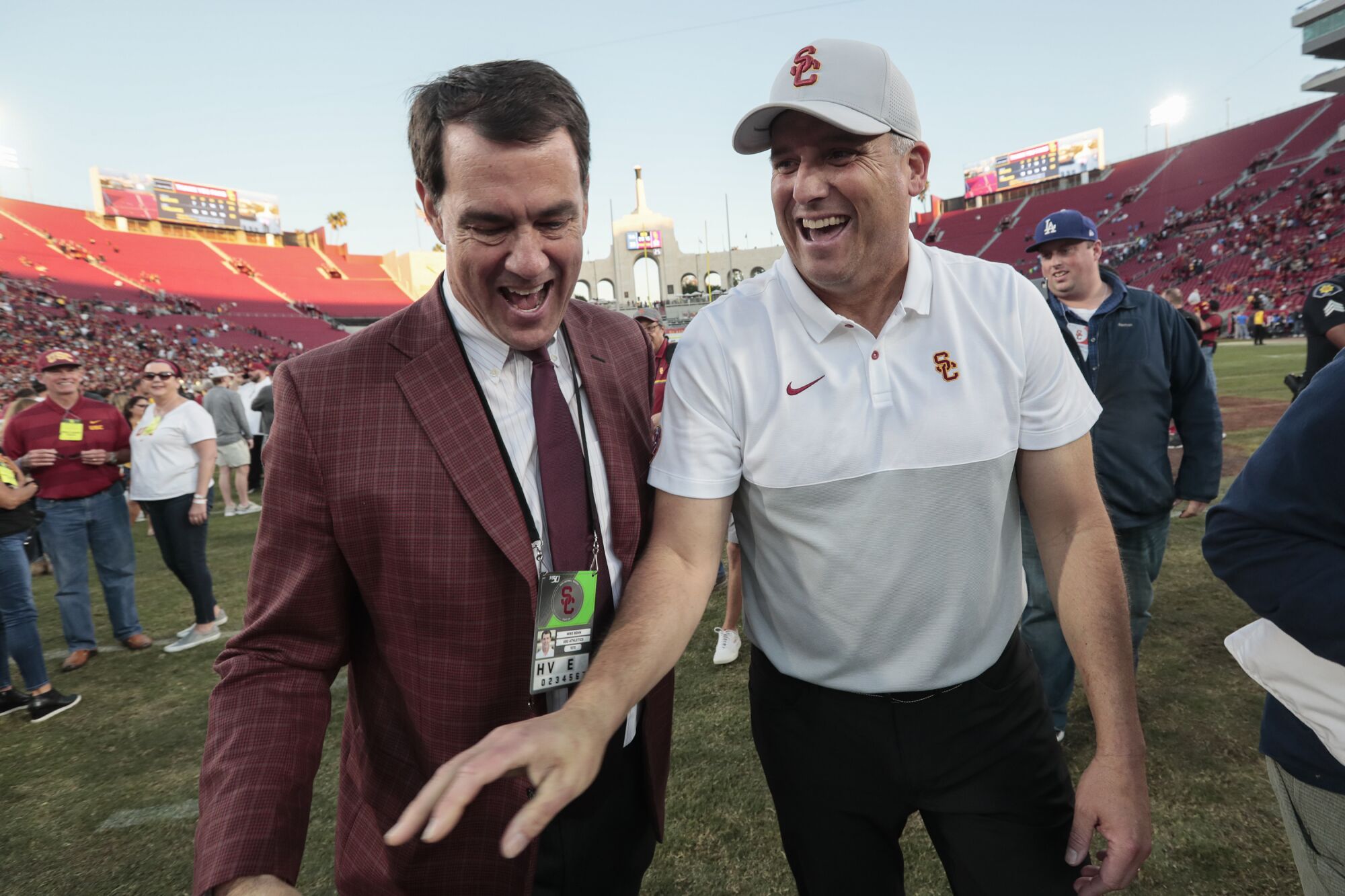 USC coach Clay Helton and athletic director Mike Bohn laugh while walking off the football field.