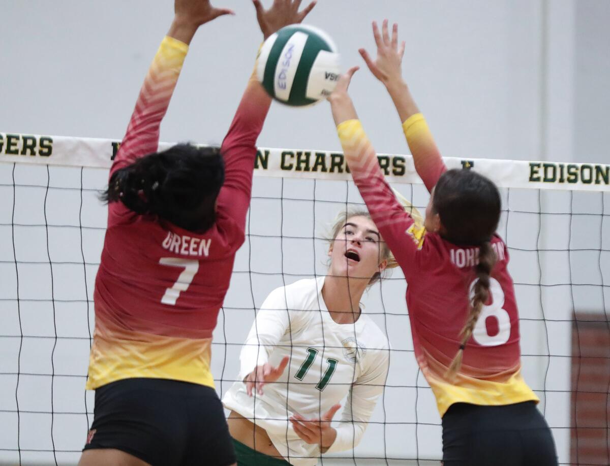 Edison's Summer Witherby (11) hits a kill between two blockers against Long Beach Wilson on Wednesday.
