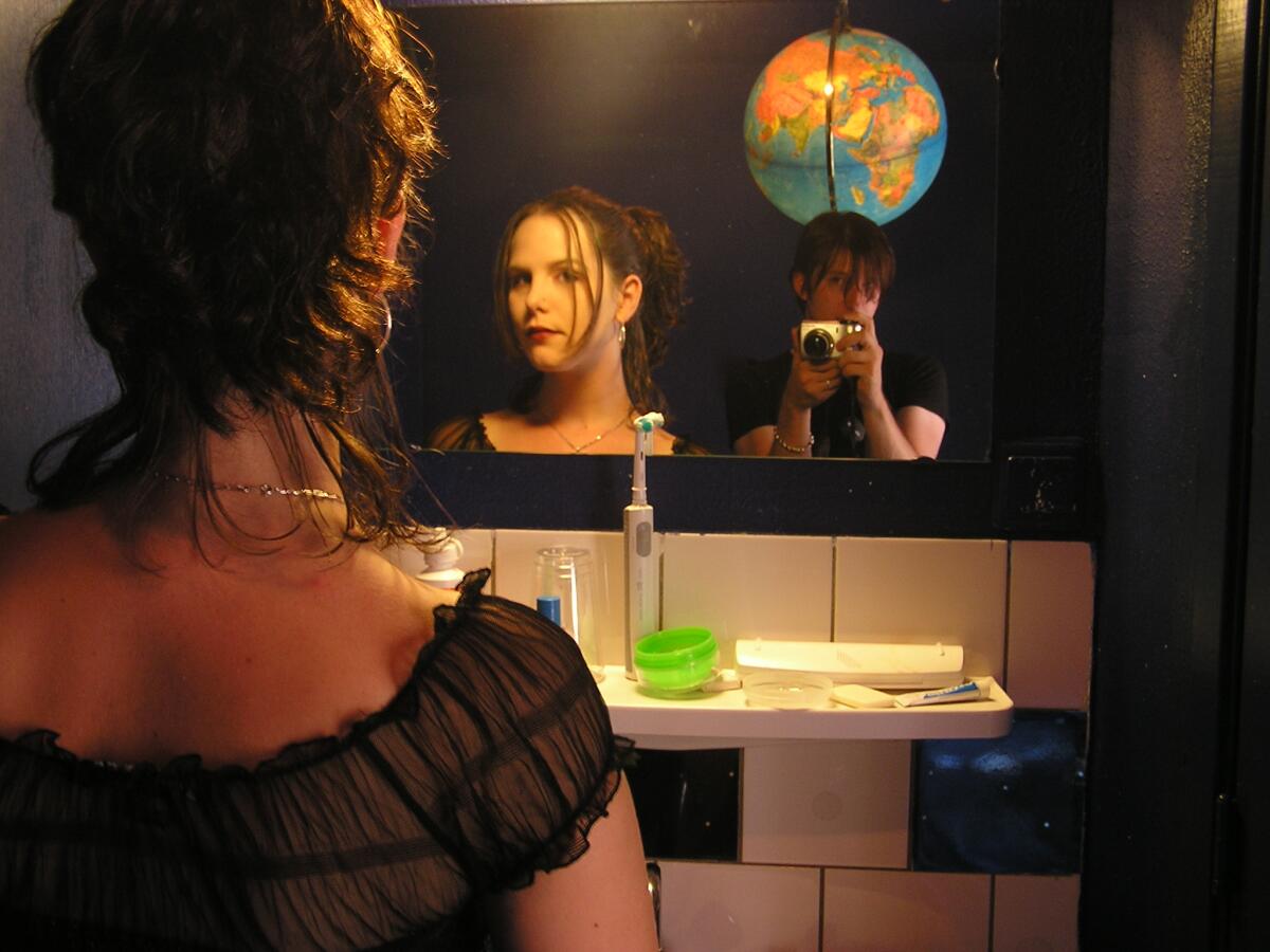 A woman is photographed looking in a mirror.
