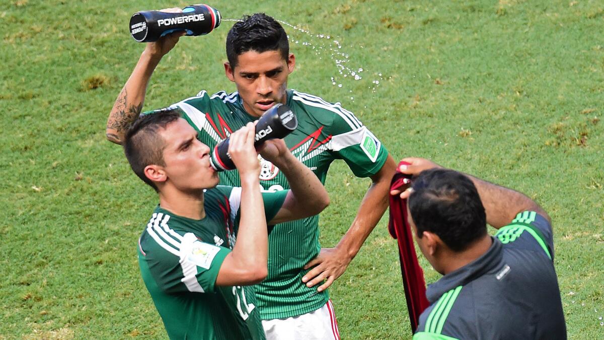 Mexico's Javier Aquino, left, and teammate Oribe Peralta cool off during a break in their World Cup match against the Netherlands on Sunday.