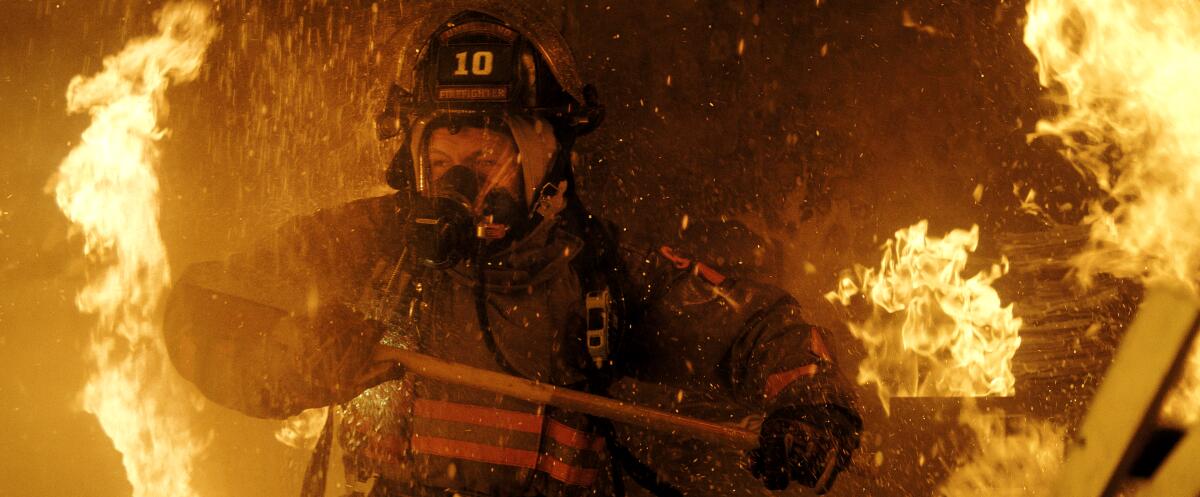 A man dressed as a firefighter surrounded by flames